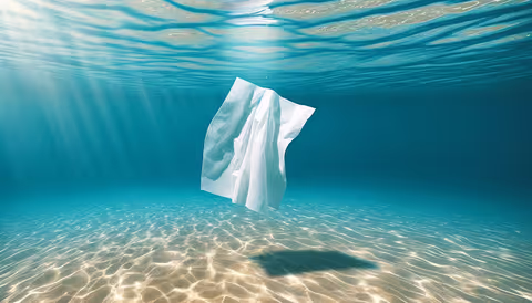 A single white wet wipe drifting underwater in the blue ocean, illustrating the wastewater and environmental impact of wet wipes